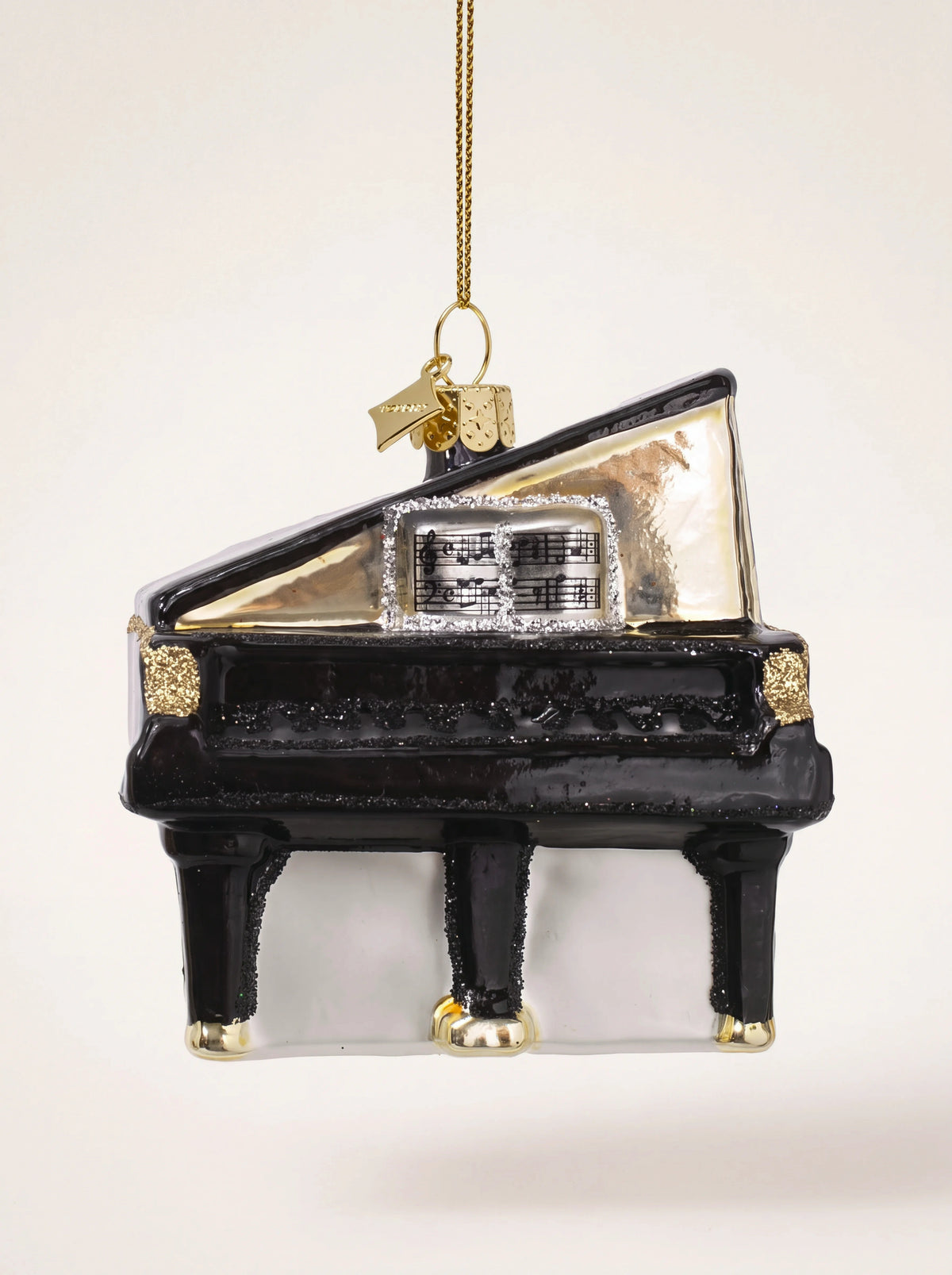 Black glass grand piano ornament with an open lid, sheet music, and gold glitter accents