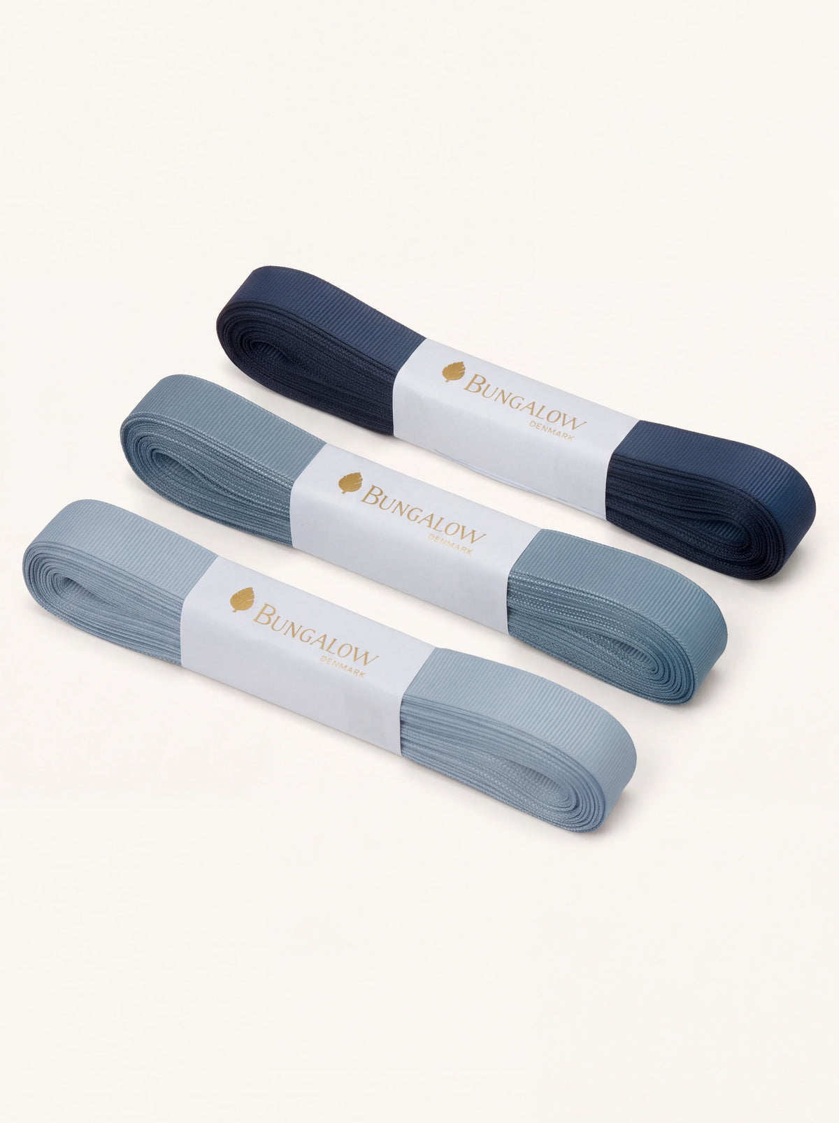 Set of three grosgrain ribbons in light, mid and navy blue with paper sleeves labelled Bungalow Denmark