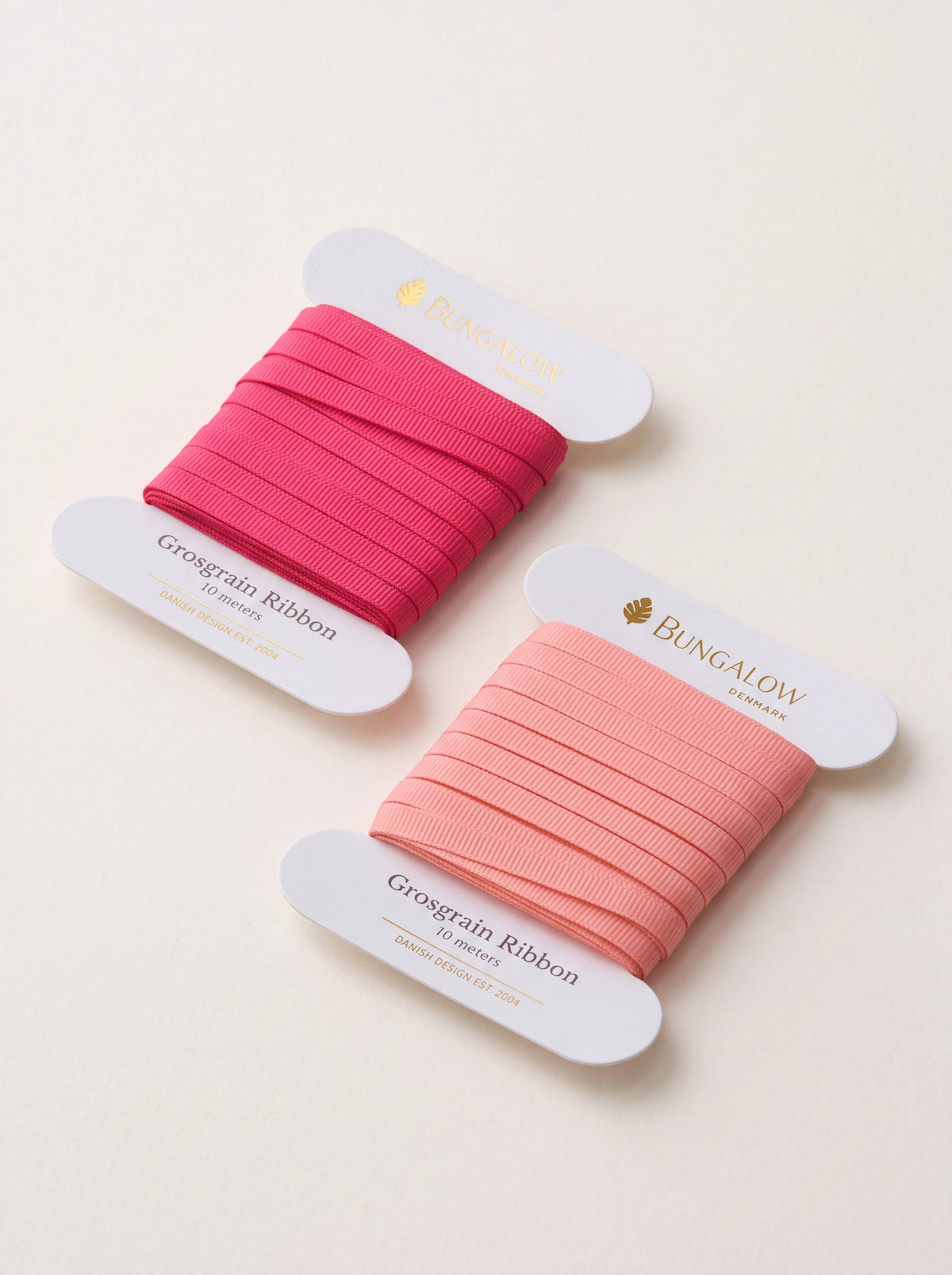 Grosgrain ribbon set in deep magenta and soft peach pink, wound on white card spools