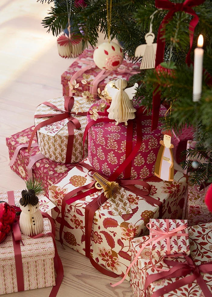 Grosgrain ribbons tied around patterned gift boxes and hanging ornaments on a Christmas tree