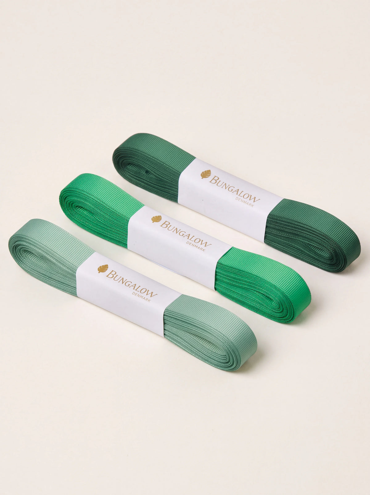 Three ribbed grosgrain ribbons in light, mid and dark green, bundled in paper bands labelled Bungalow Denmark