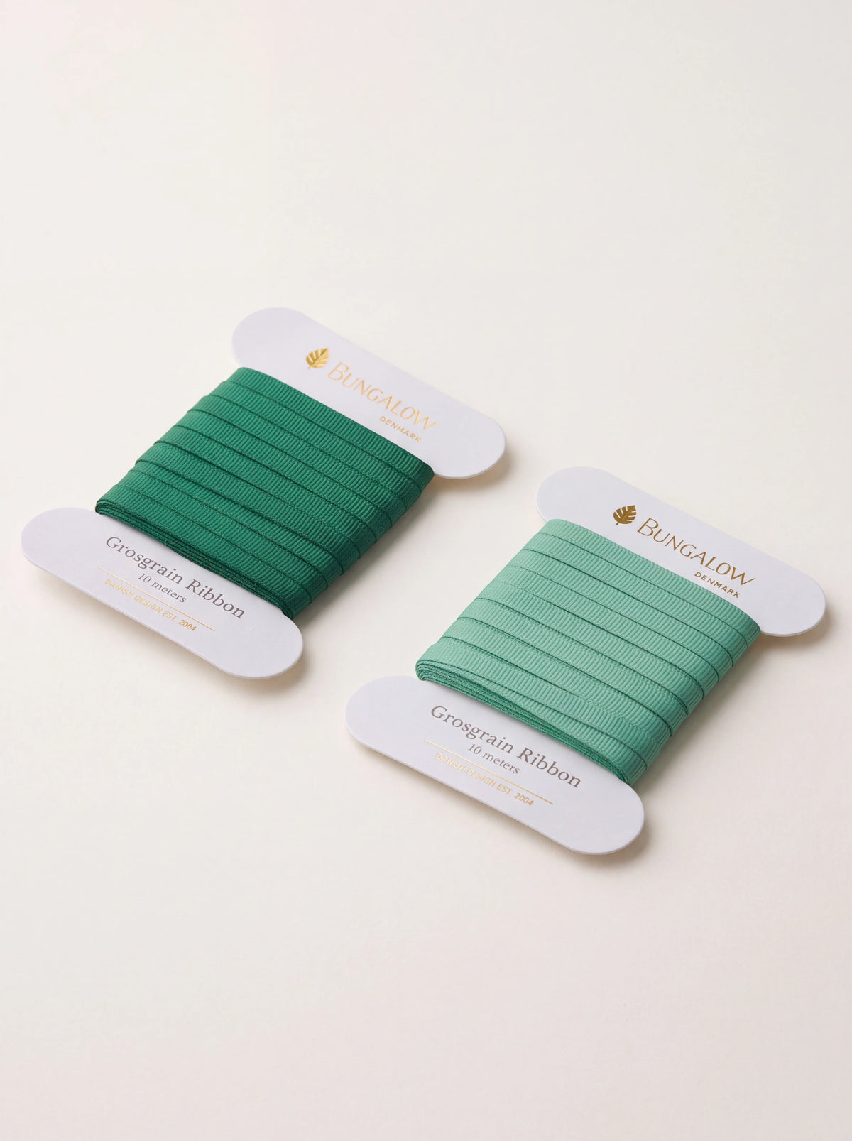 Grosgrain ribbon set in dark green and sage green, wound on white cardboard spools