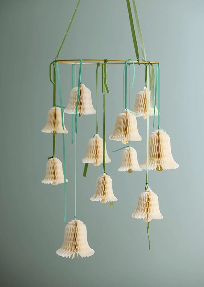 Green grosgrain ribbons used to hang cream paper honeycomb bells from a circular mobile