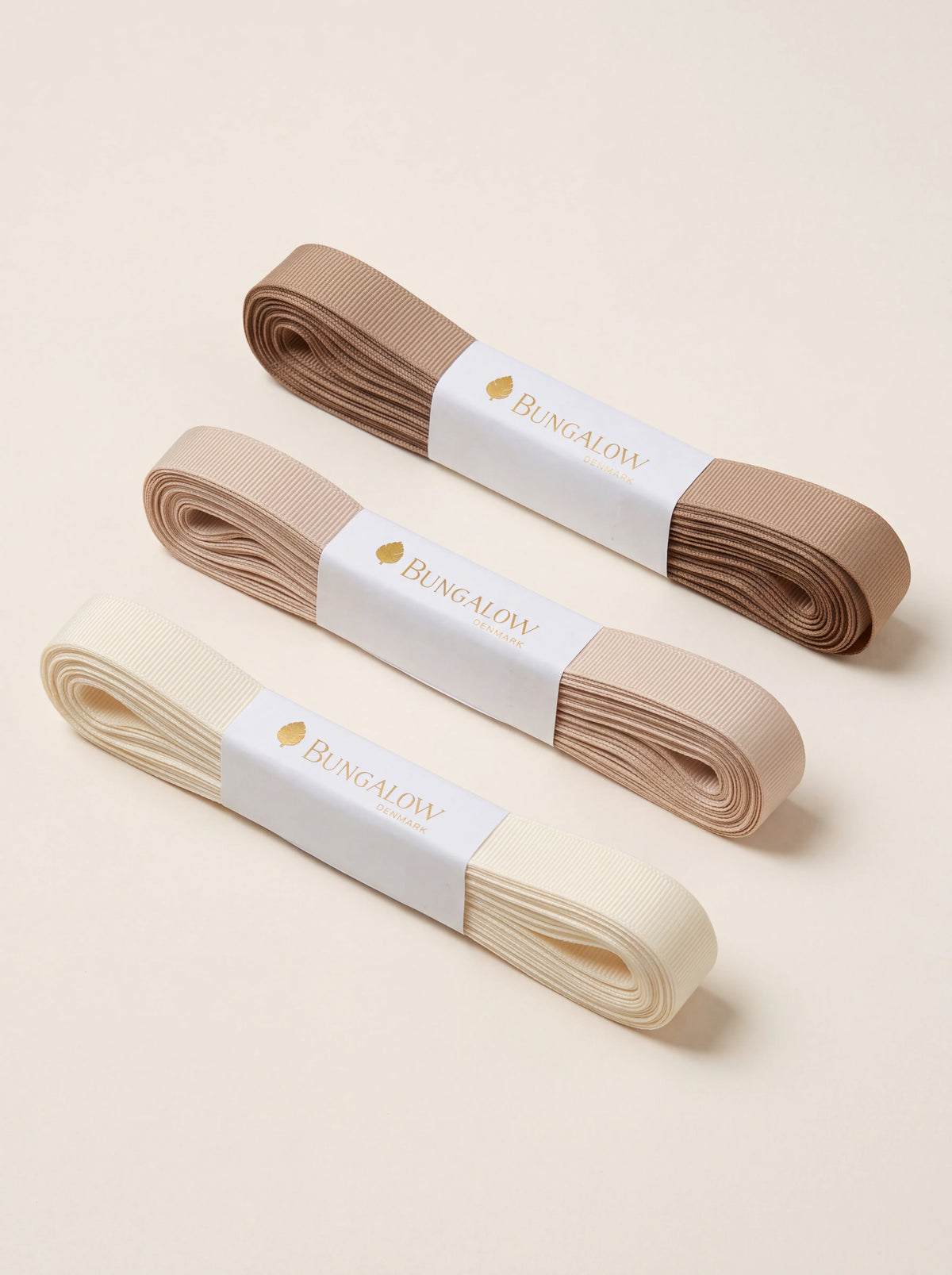 Set of three ribbed grosgrain ribbons in cream, light beige and latte brown, bundled in paper bands