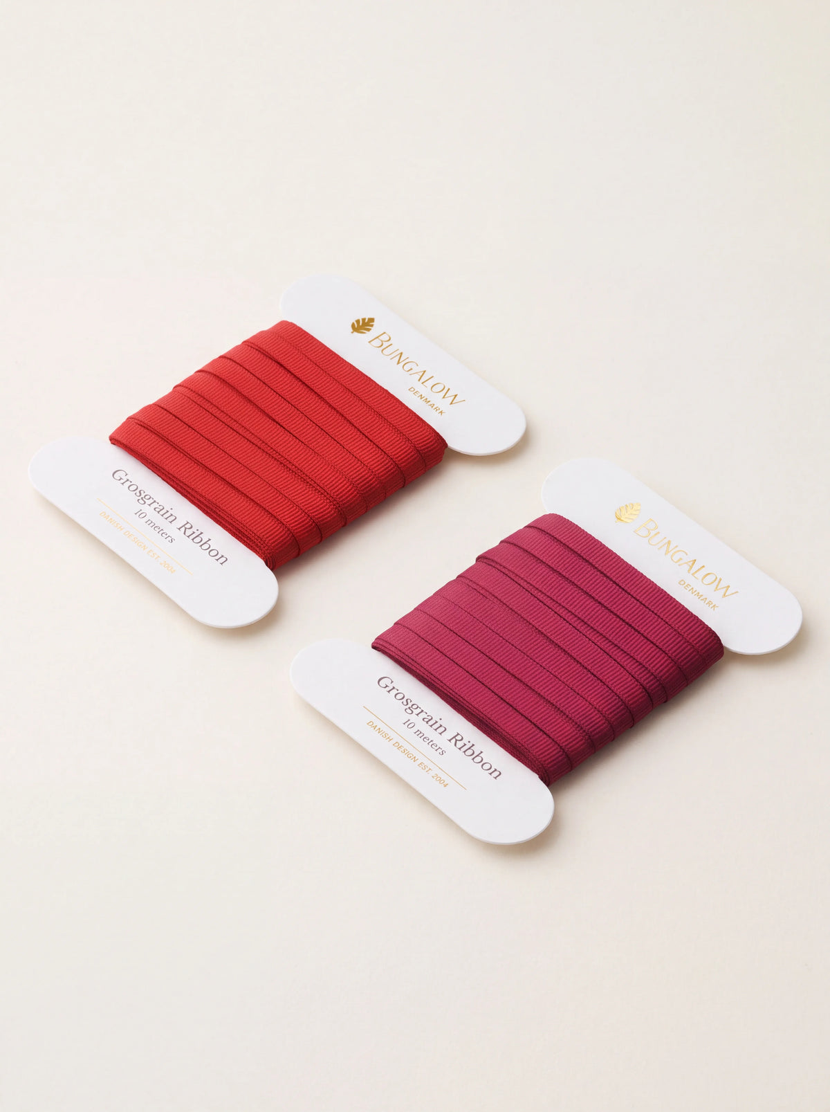 Two flat spools of ribbed polyester grosgrain ribbon in red and wine shades