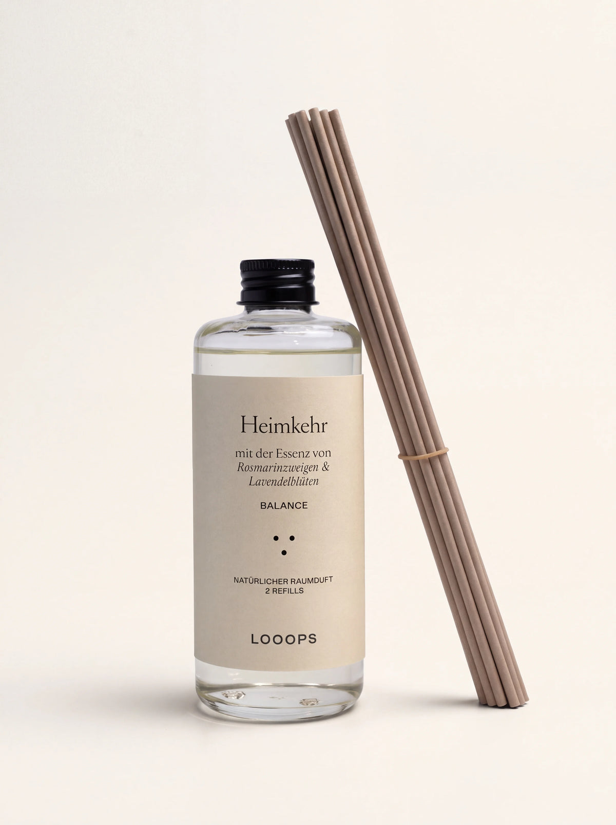 Reed diffuser refill in a clear glass bottle with a black screw cap, alongside a bundle of paper reeds