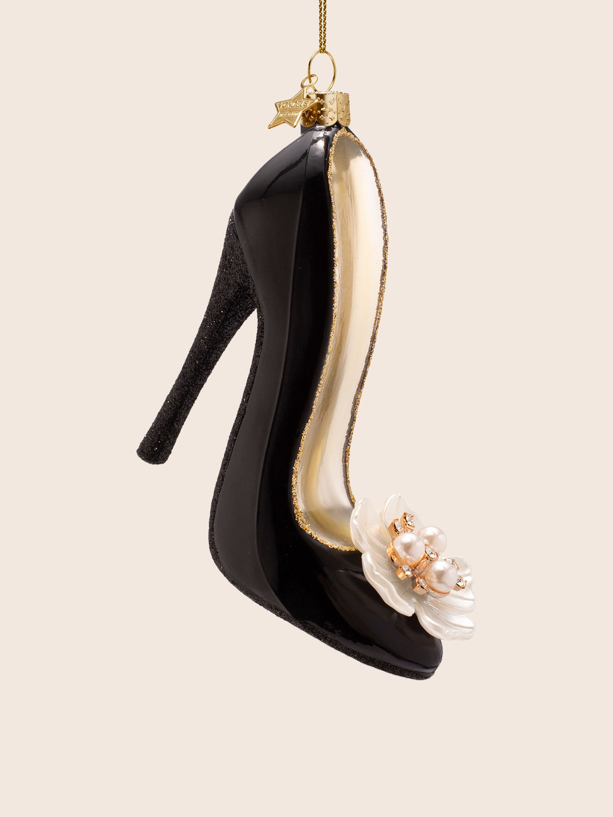 Three-quarter view showing the black glitter stiletto heel and the pearl-centred flower detail