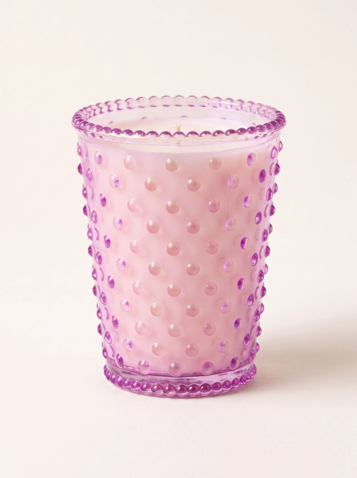 Scented candle in a lilac hobnail glass vessel with pale wax and a single wick