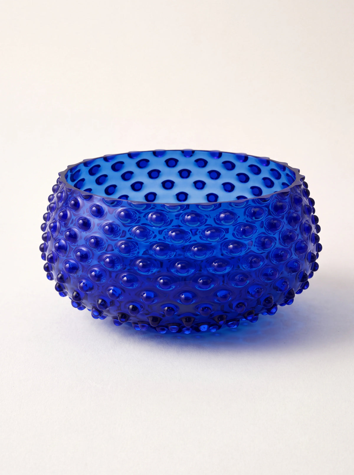 Round dark blue hand-blown glass bowl with an all-over hobnail texture and flat rim