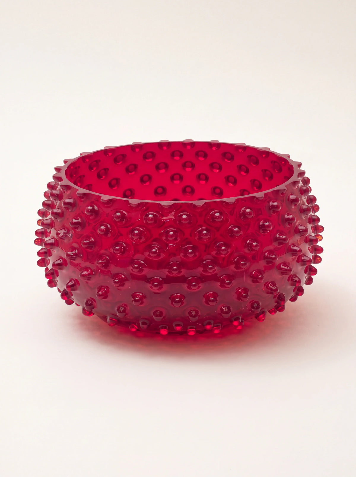 Round garnet red hobnail glass bowl with raised studs across the curved exterior