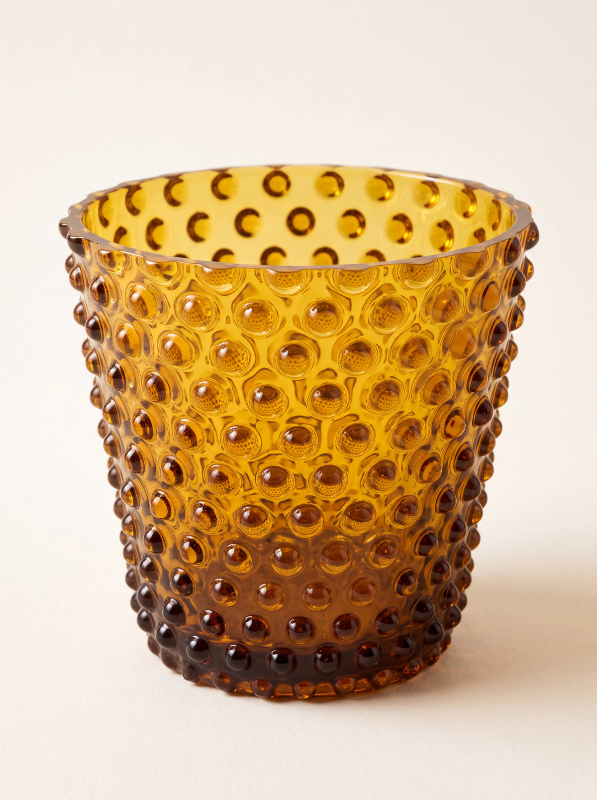 Amber hobnail glass tealight holder with a raised studded texture and tapered cylindrical shape