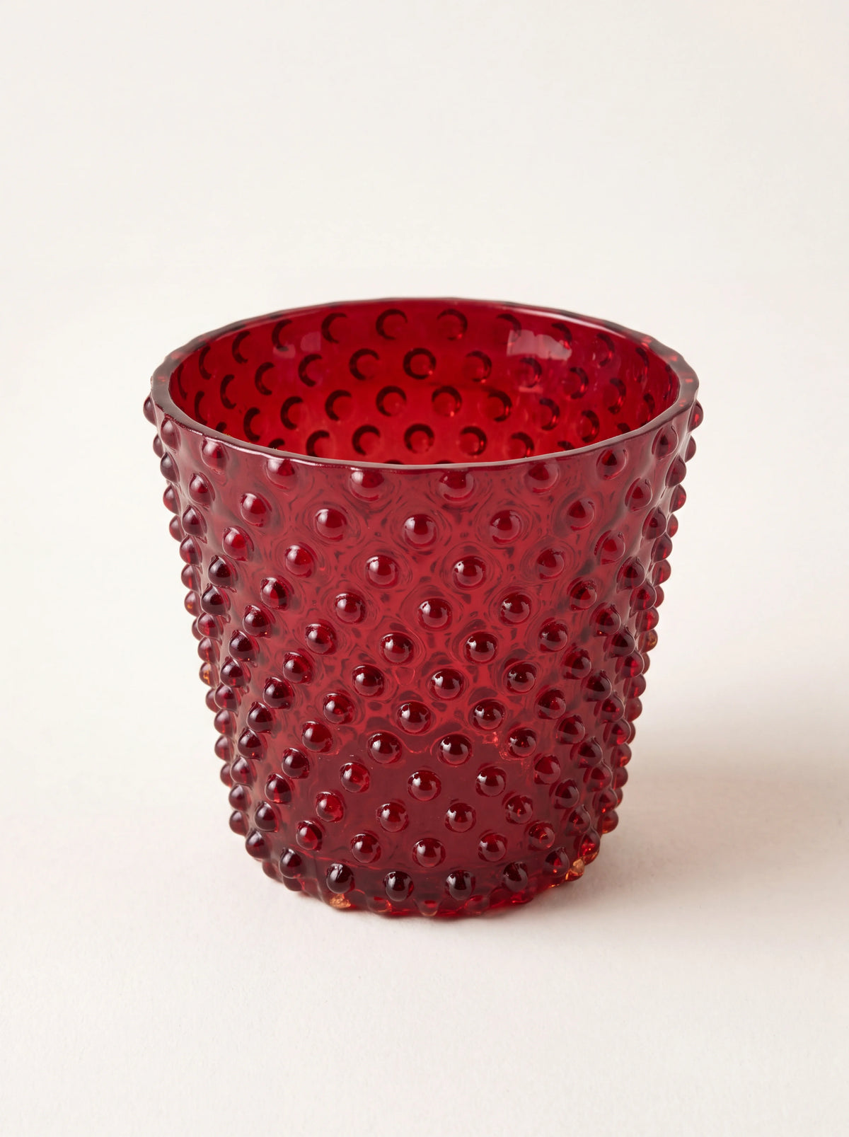 Garnet red hobnail glass tealight holder with a tapered shape and smooth rim