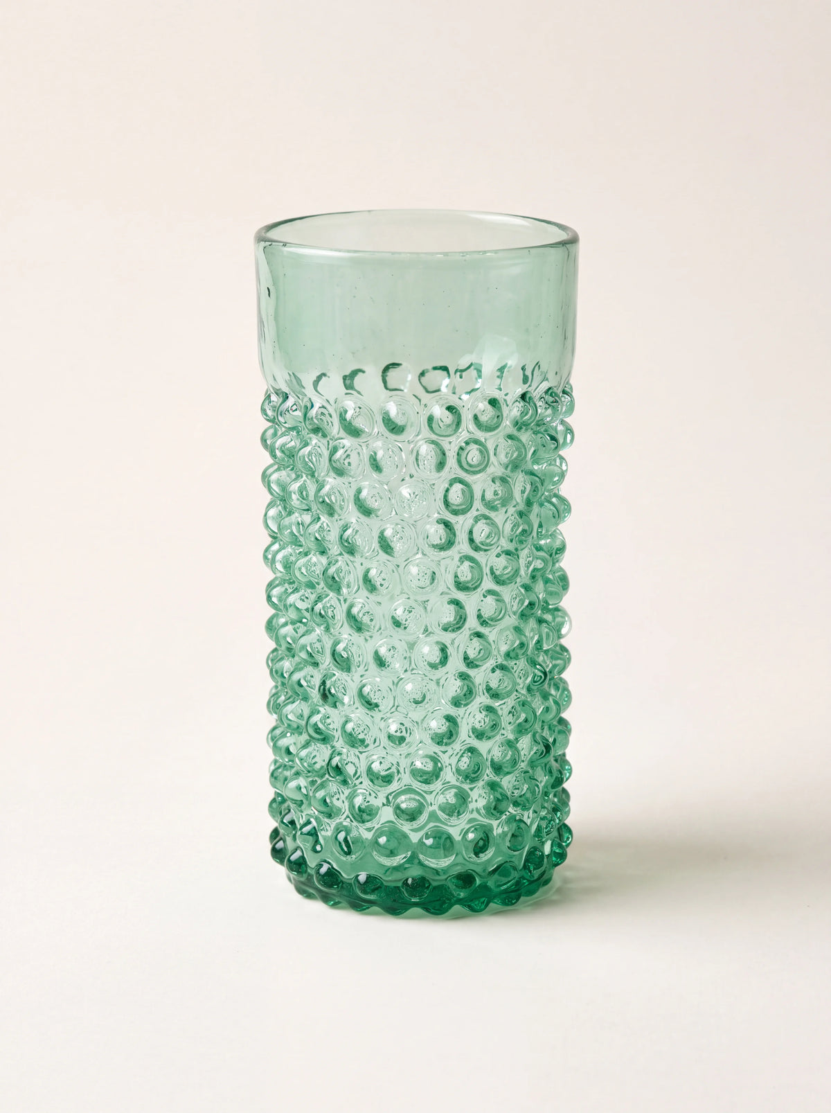 Tall light green glass tumbler with raised hobnail texture and a smooth rim