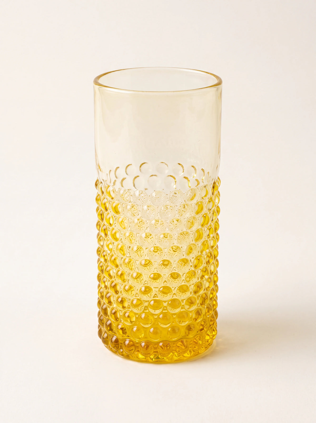 Cylindrical yellow glass tumbler with a raised hobnail texture on the lower half and a smooth top
