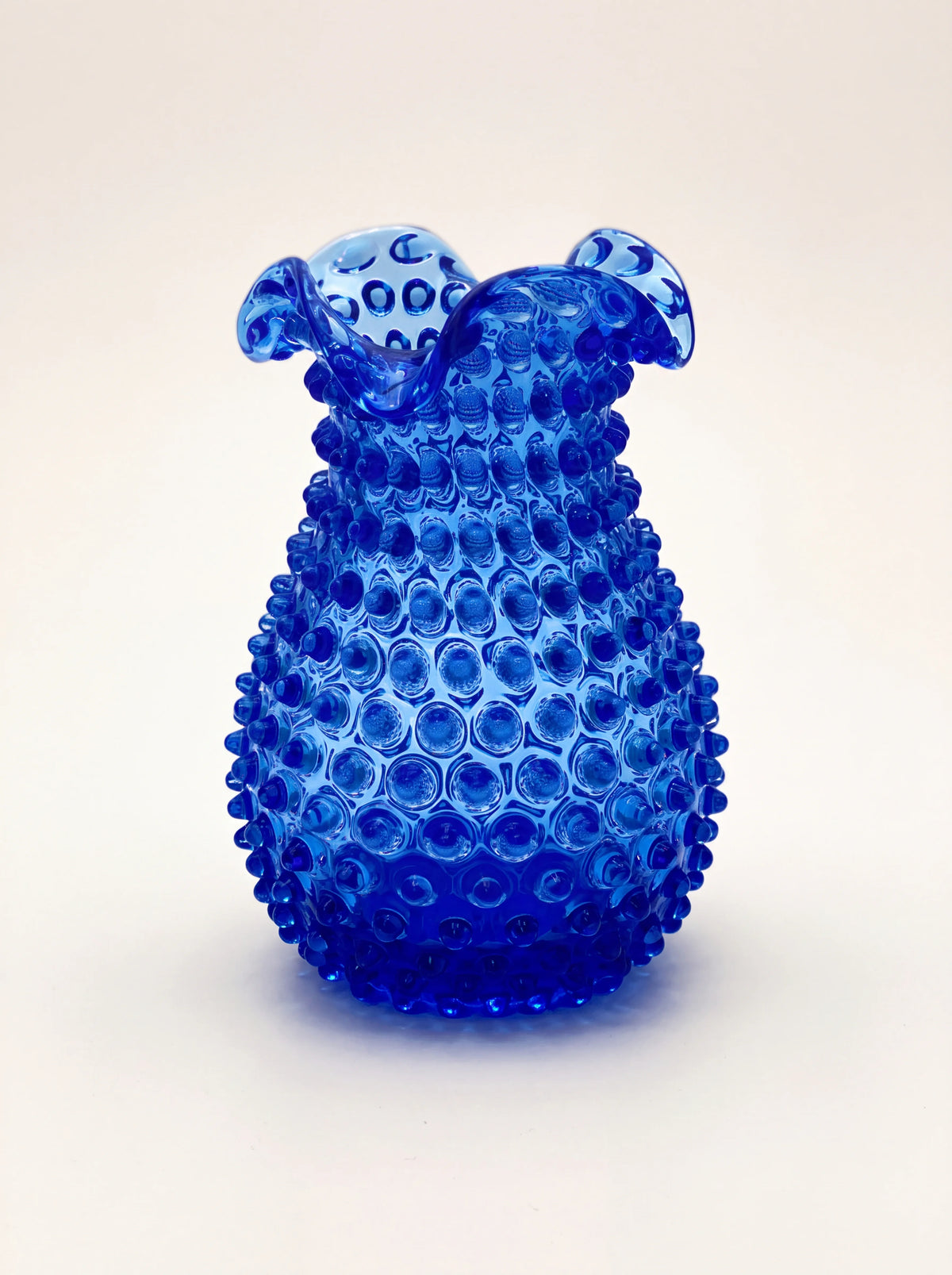 Blue hobnail glass vase with a bulbous body and ruffled rim