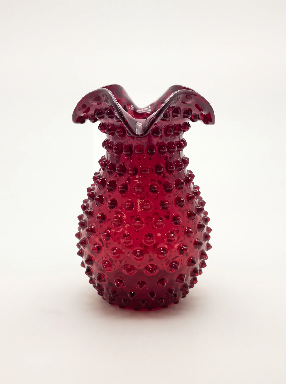 Garnet hobnail glass vase with a bulbous body and flared, ruffled rim