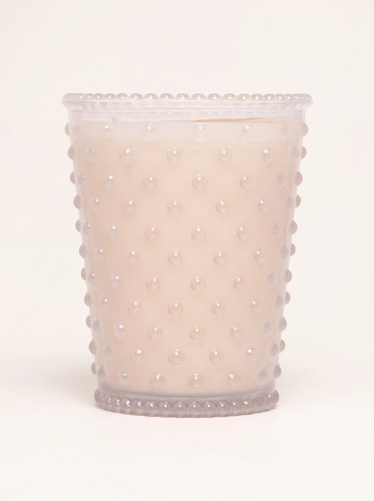 Scented candle in a frosted hobnail glass vessel with beaded rims, filled with cream wax