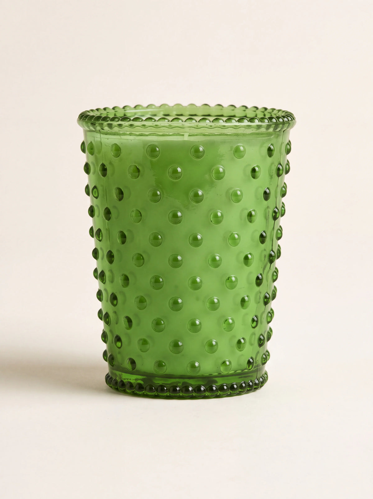 Scented candle in a green hobnail glass vessel with beaded rims and green wax