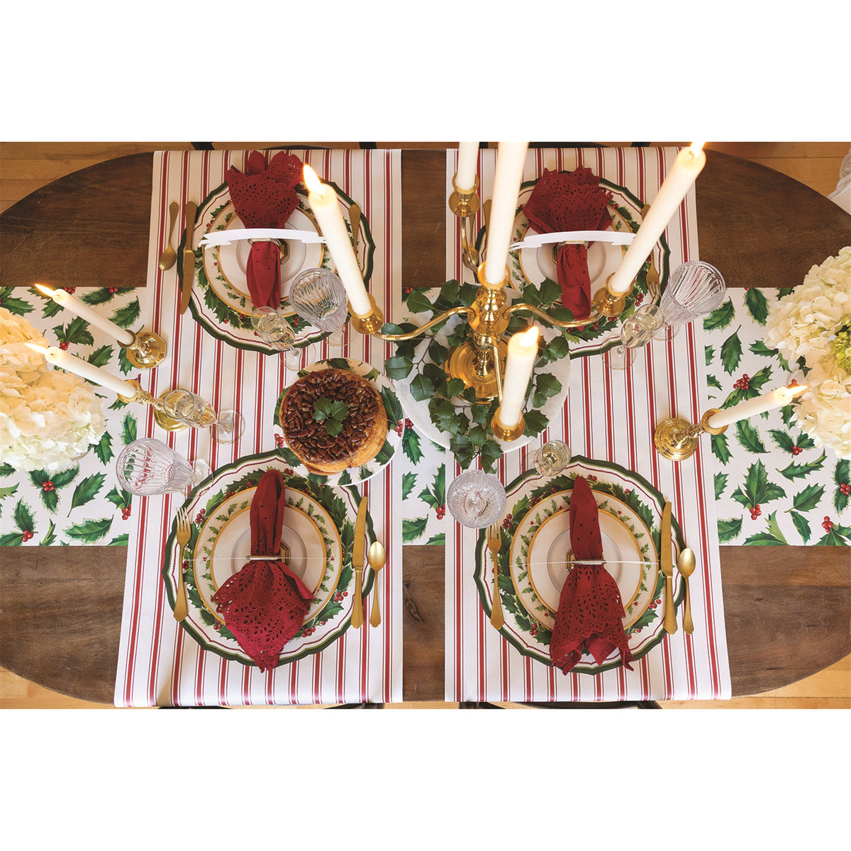 Holly paper placemats arranged on a wooden dining table with four place settings and a central candelabra