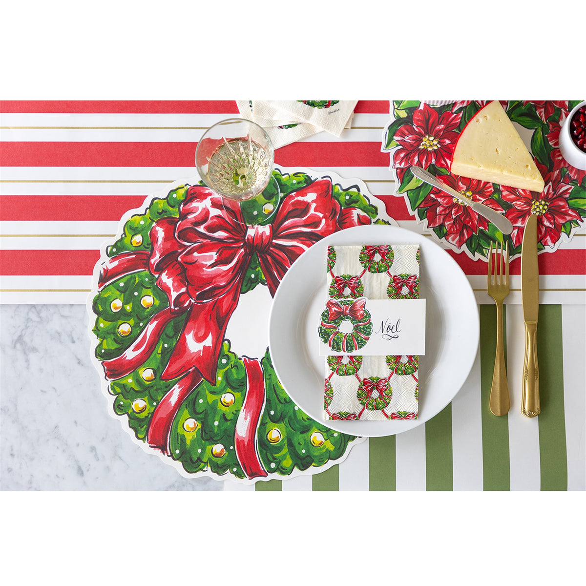 Wreath napkin folded on a white dinner plate with a place card reading "Noël" in a festive table setting
