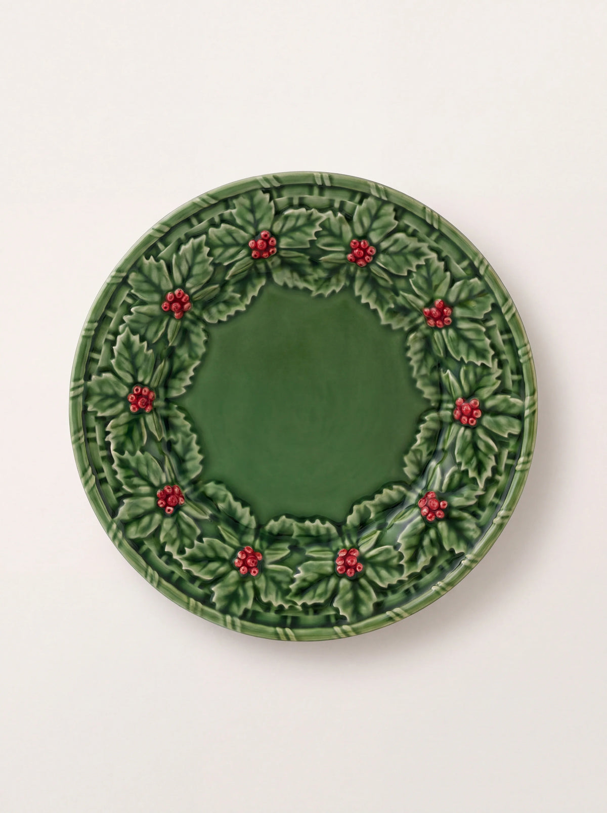 Green glazed earthenware dessert plate with relief holly leaves and red berries along the rim