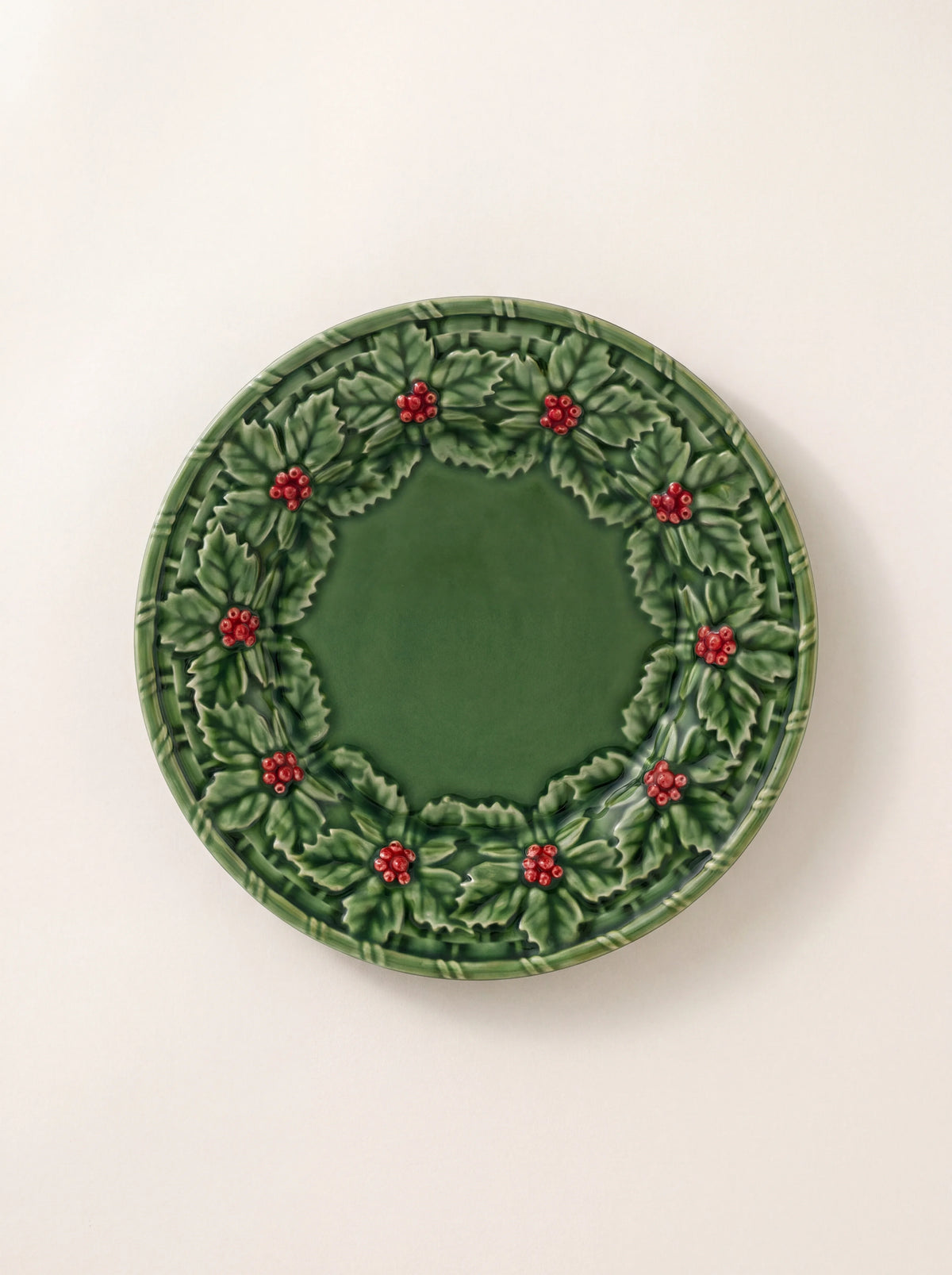 Glazed green earthenware dinner plate with an embossed relief rim of holly leaves and red berries
