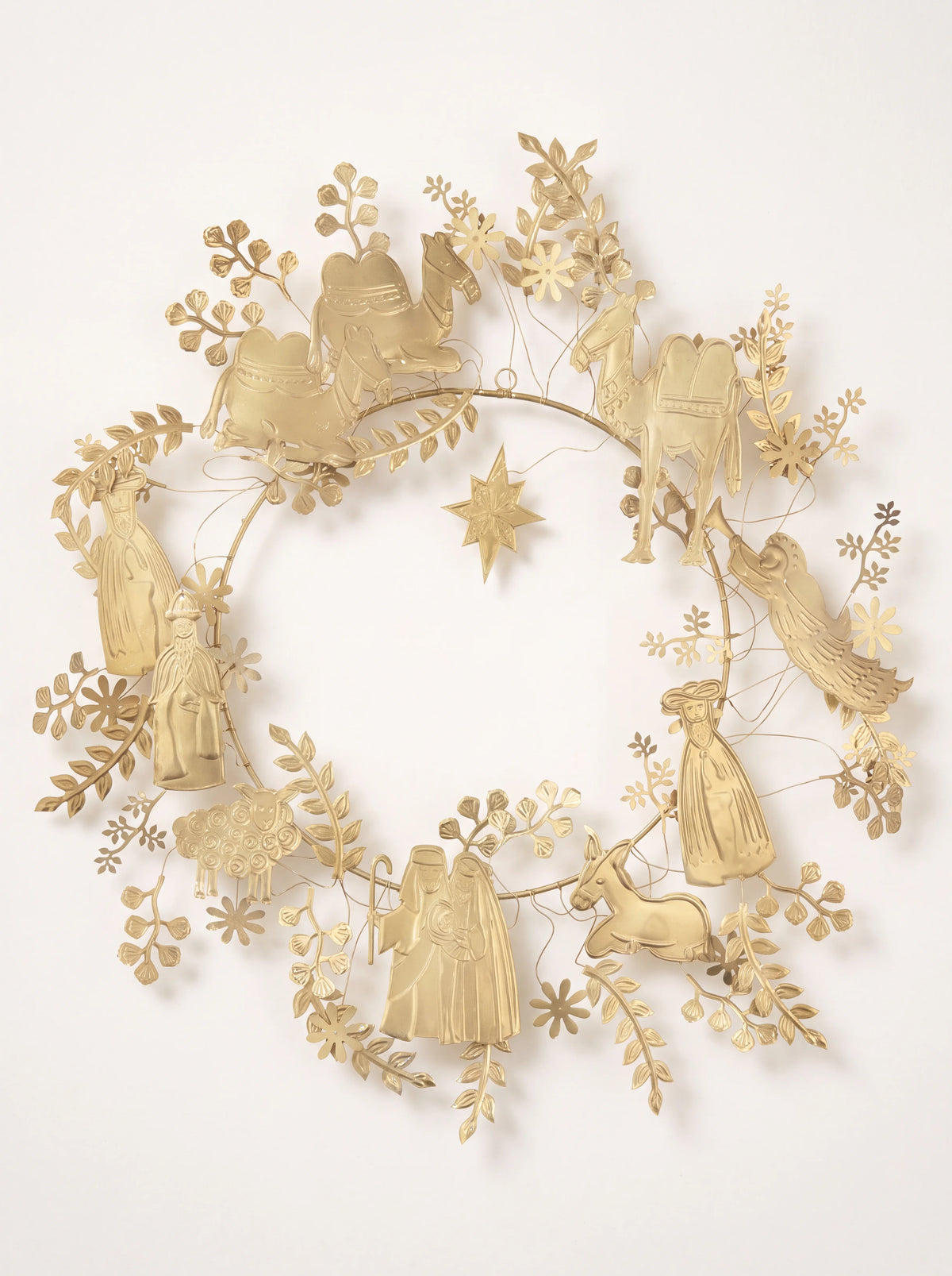 Golden metal wreath with stamped nativity figures, foliage details, and a star suspended in the centre