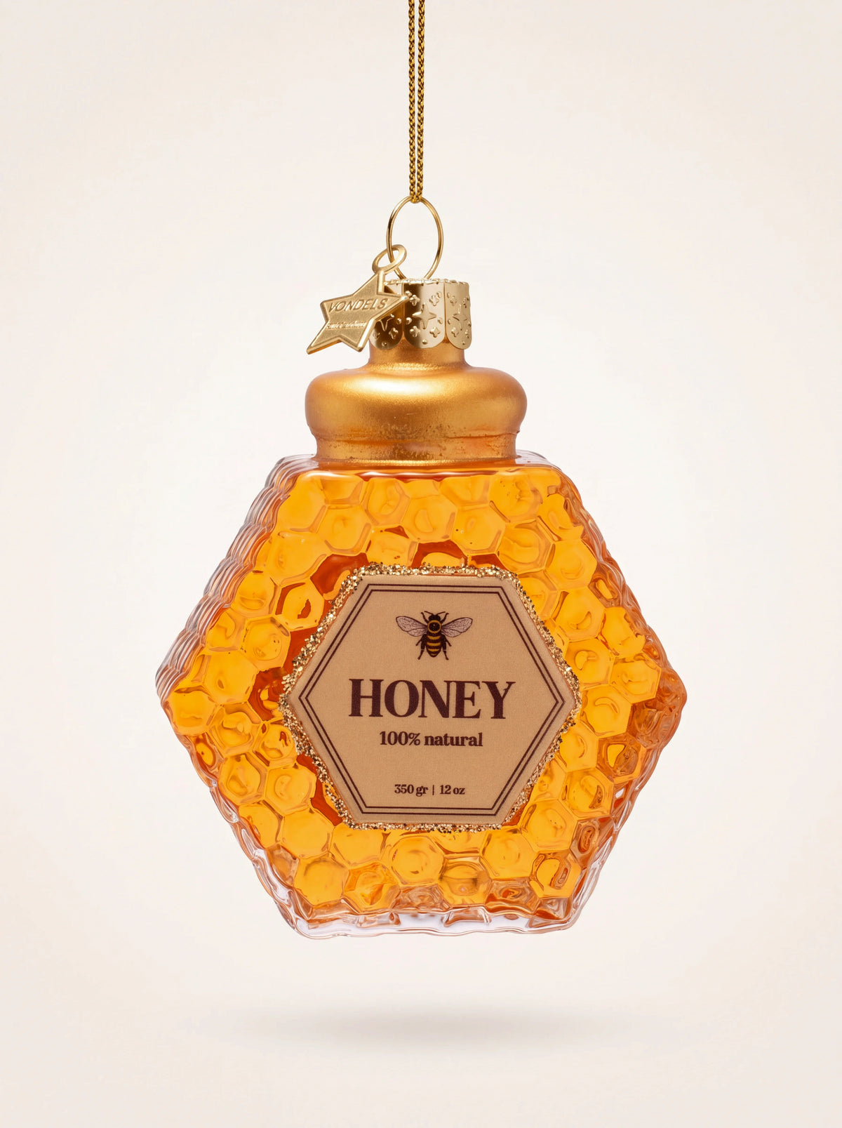 Amber glass honey jar ornament with a hexagonal shape, honeycomb texture, printed label and gold lid