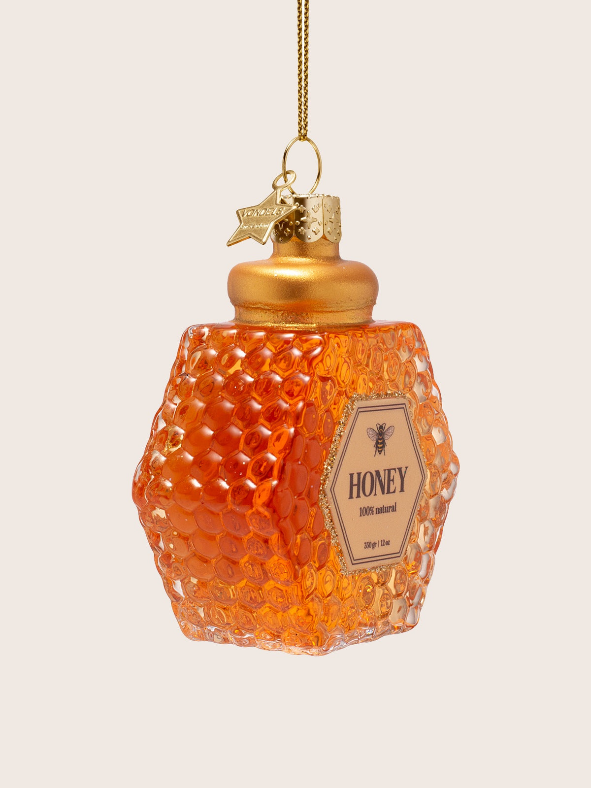 Three-quarter view showing the faceted depth and embossed honeycomb texture of the amber glass jar