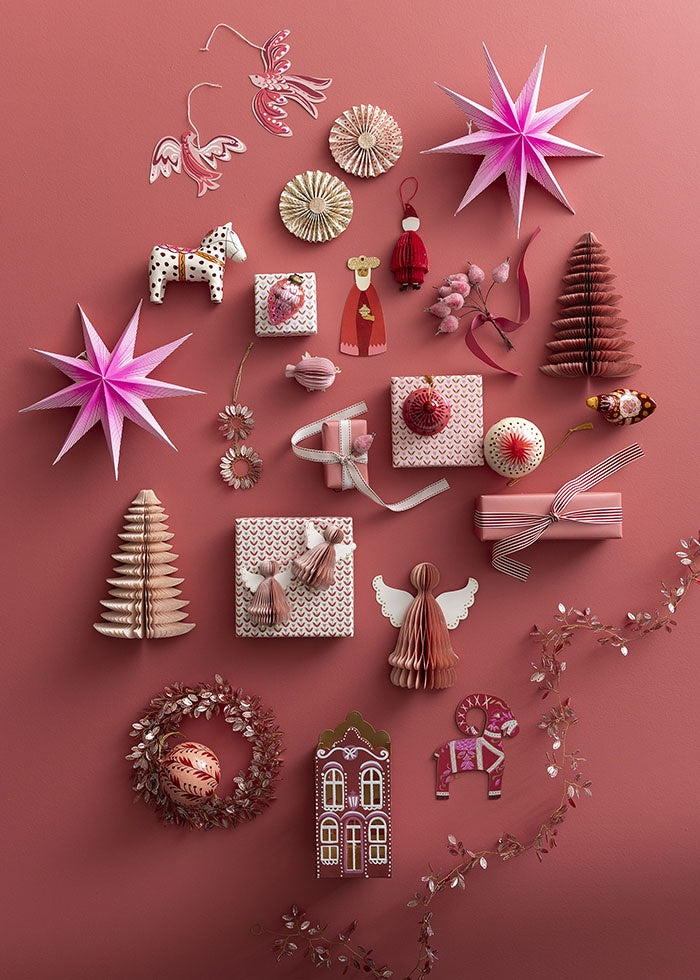 Pink honeycomb paper pig ornament styled among festive paper decorations and wrapped gifts