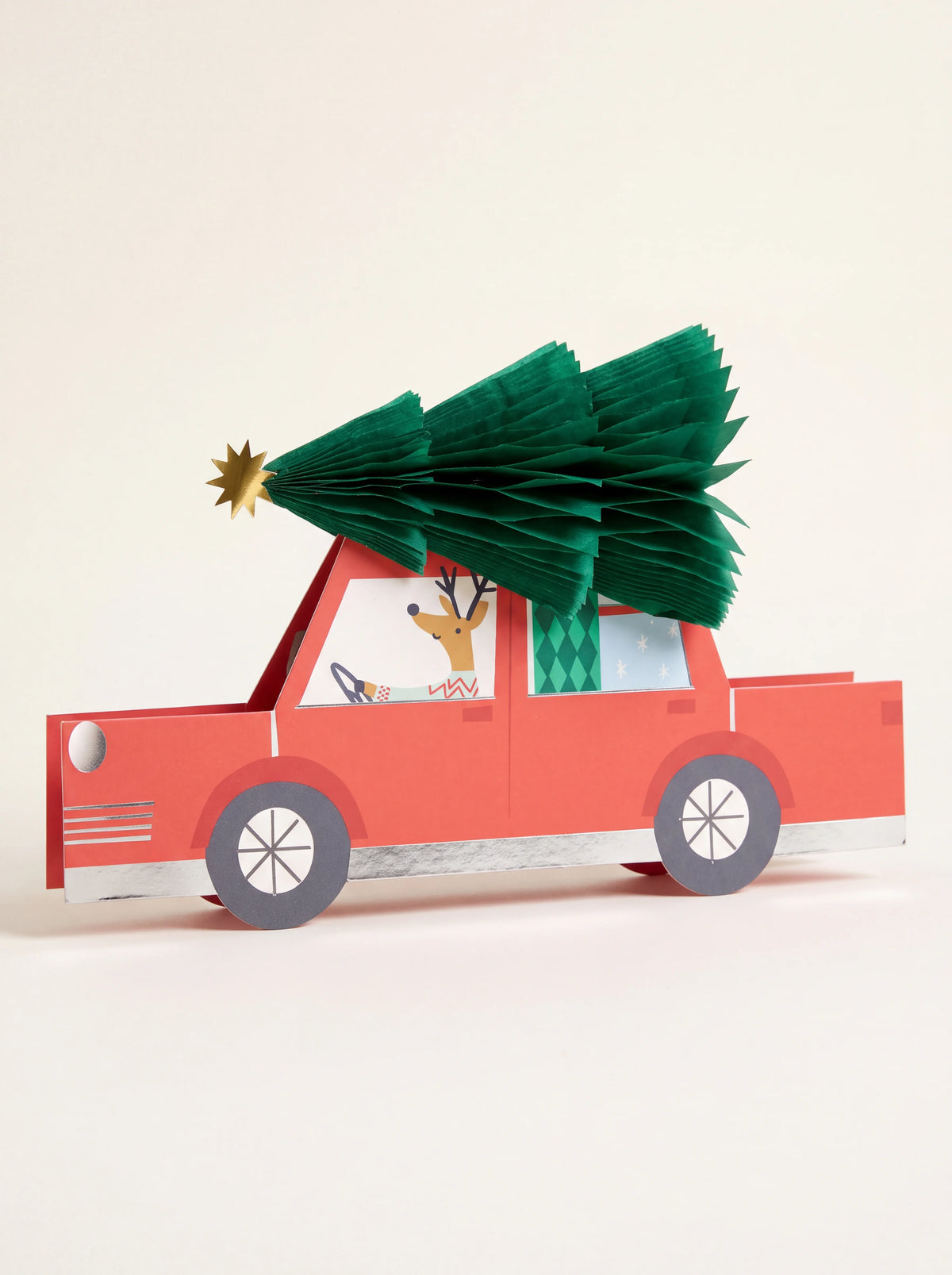 Red car 3D paper greeting card with a green honeycomb Christmas tree on the roof and reindeer driver