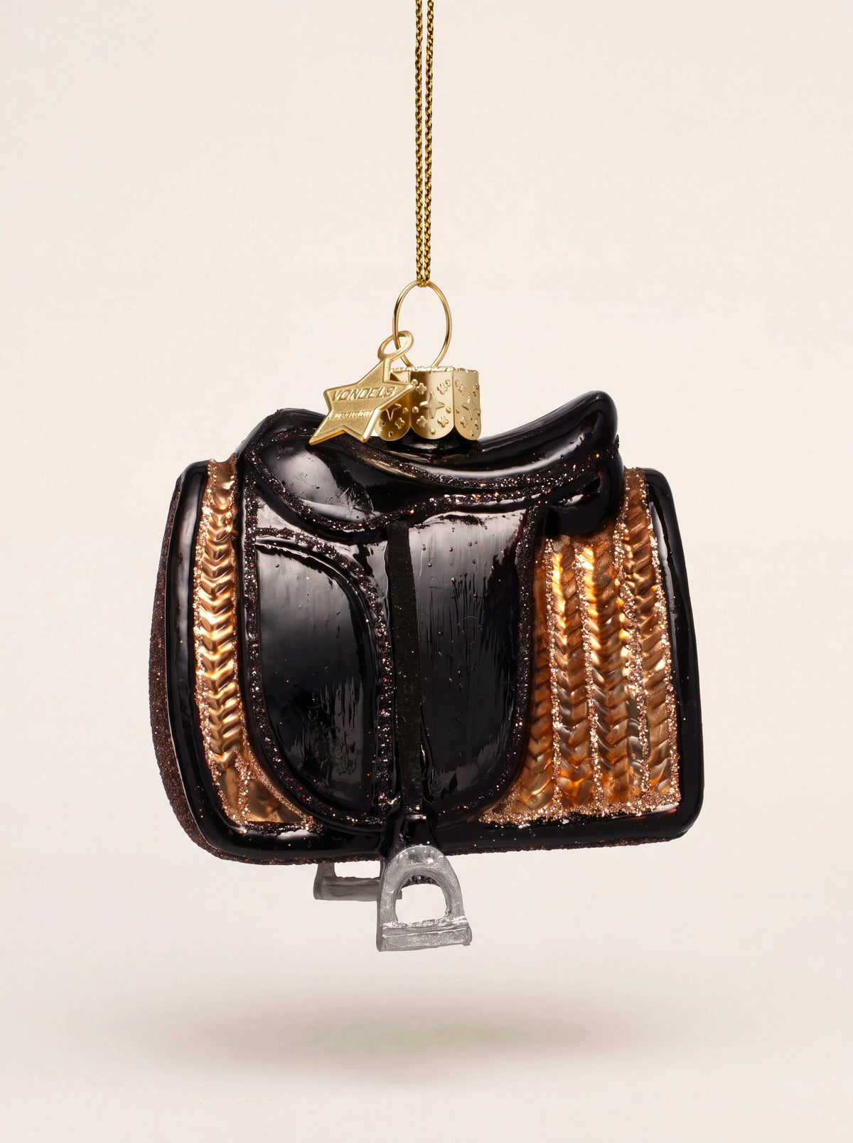 Black glass horse saddle ornament with a textured bronze-tone pad, glitter edging and a hanging stirrup