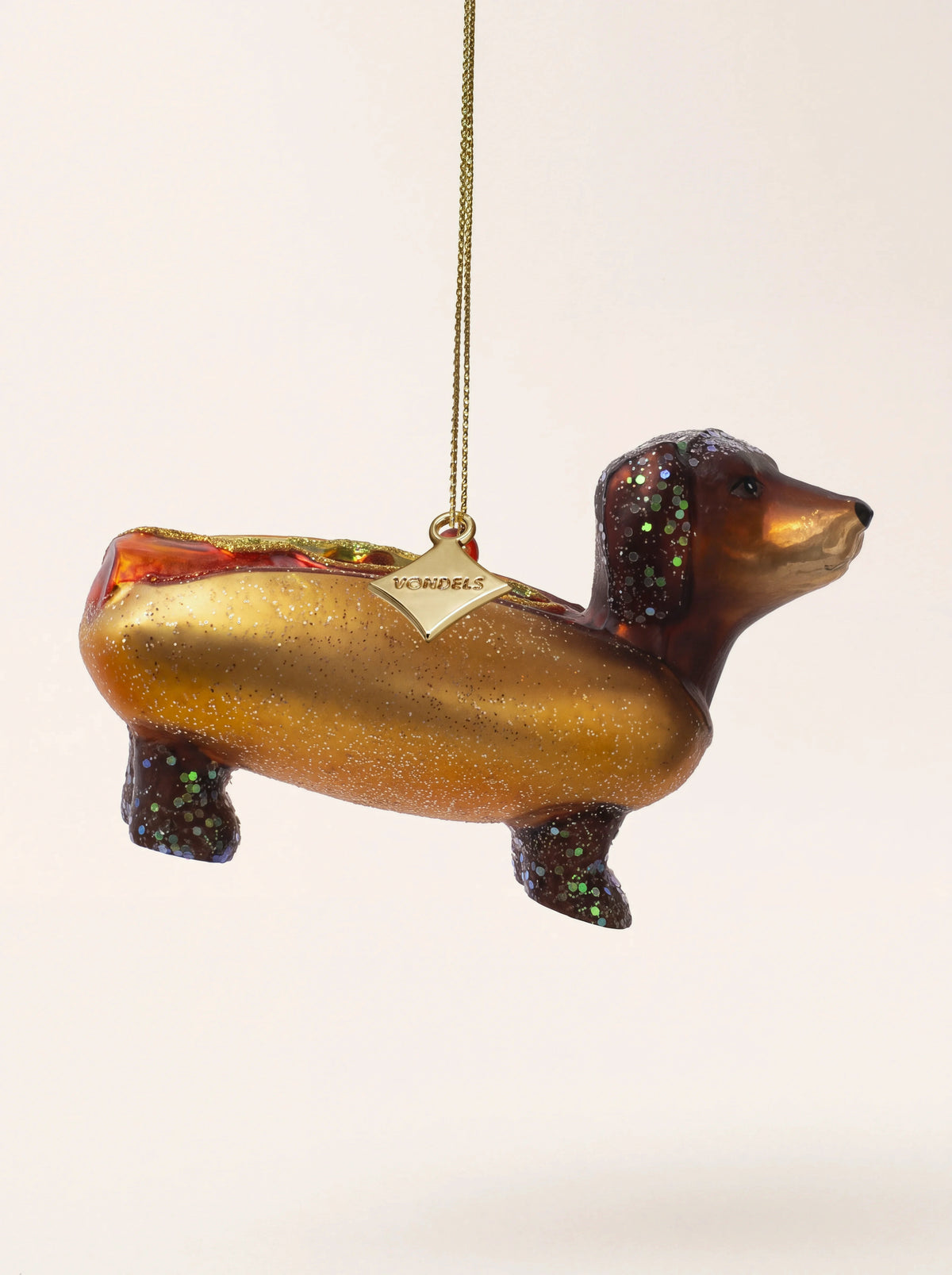 Glass dachshund hotdog Christmas ornament with glitter accents, hanging in profile from a gold cord