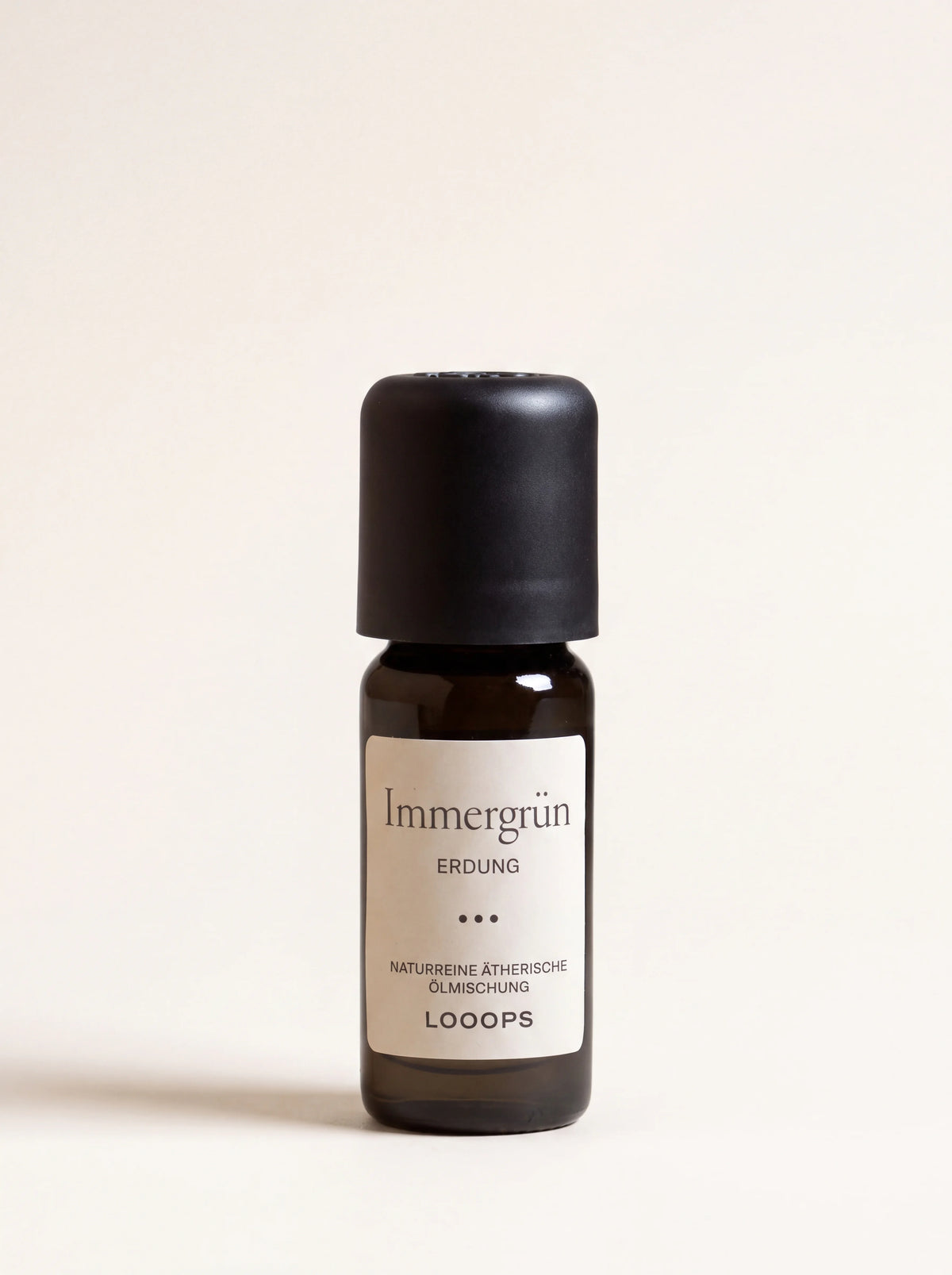 Amber glass bottle of essential oil with a matte black cap, labelled Immergrün Erdung