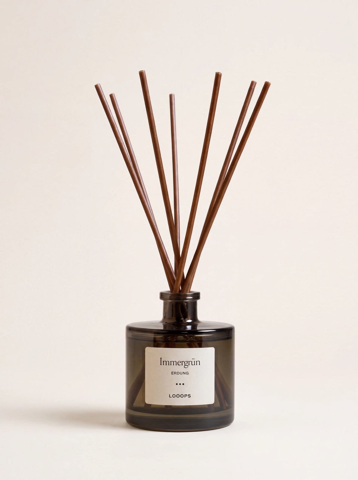 Tinted glass reed diffuser with brown paper reeds and label reading Immergrün