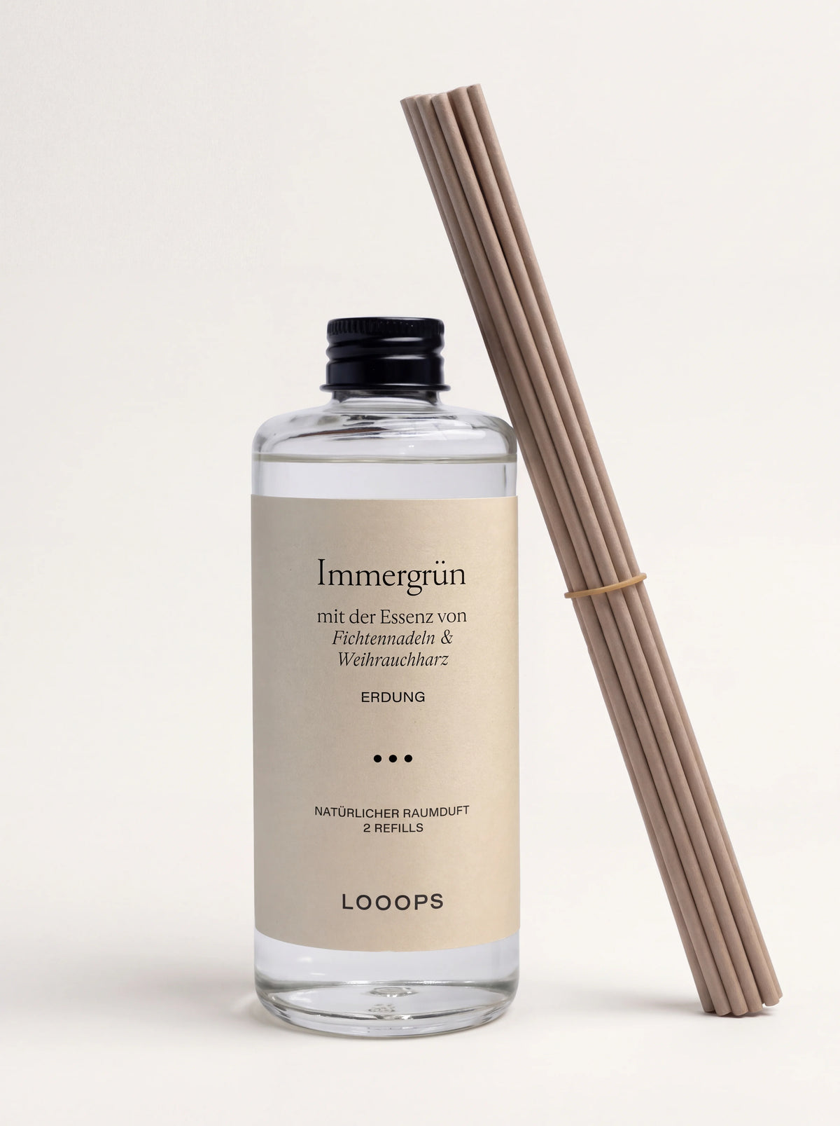 Reed diffuser refill in a clear glass bottle with a black screw cap, beside a bundle of diffuser reeds