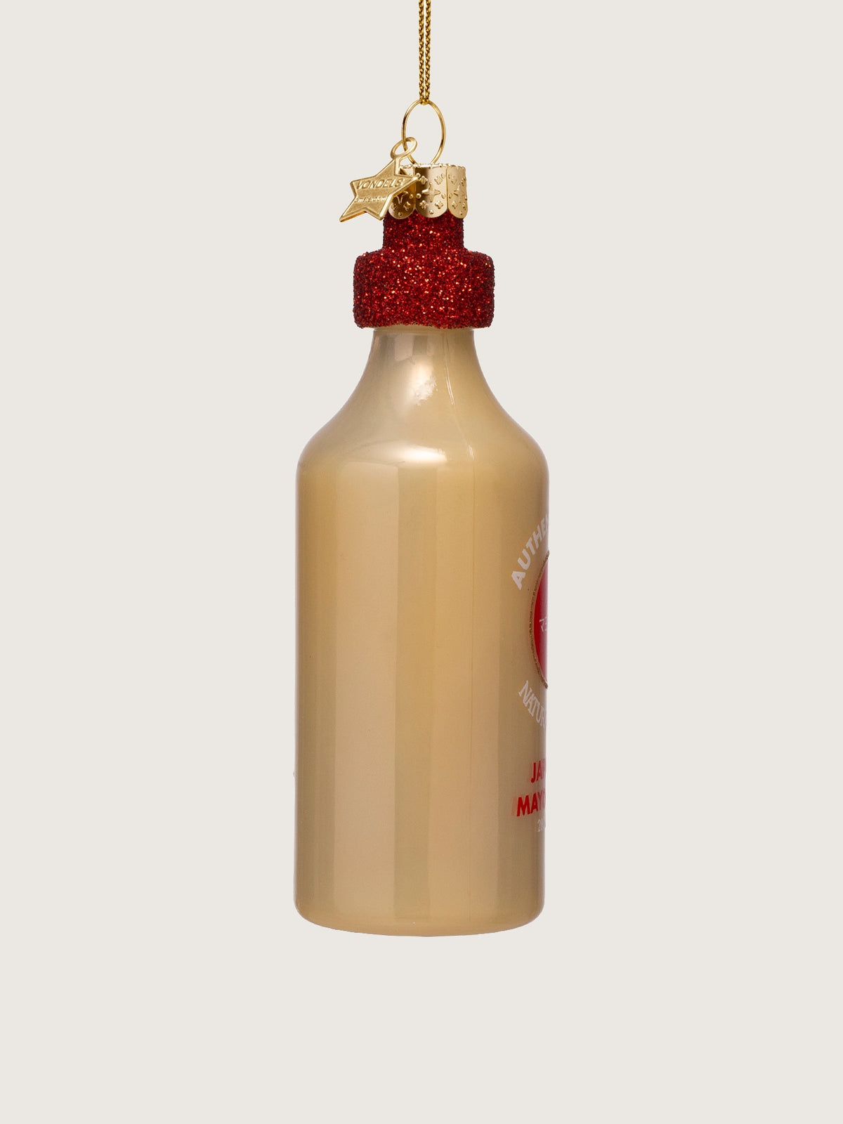 Side view of the glass ornament showing the plain beige bottle body and red glitter cap