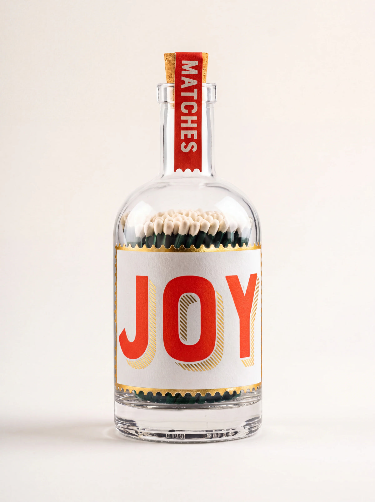 Clear glass bottle of matches with a cork stopper, red MATCHES seal and label reading JOY