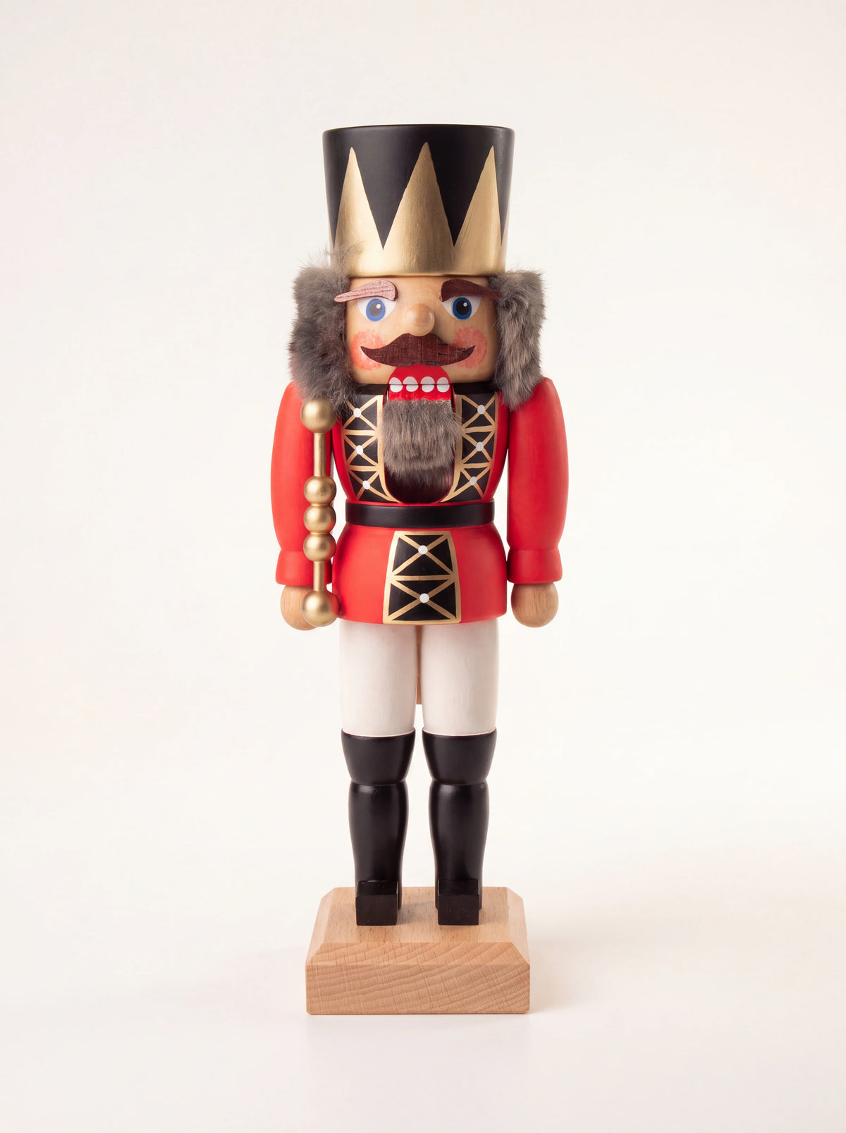 Red wooden king nutcracker with a pointed gold crown, faux-fur beard, sceptre and red uniform on a wooden base
