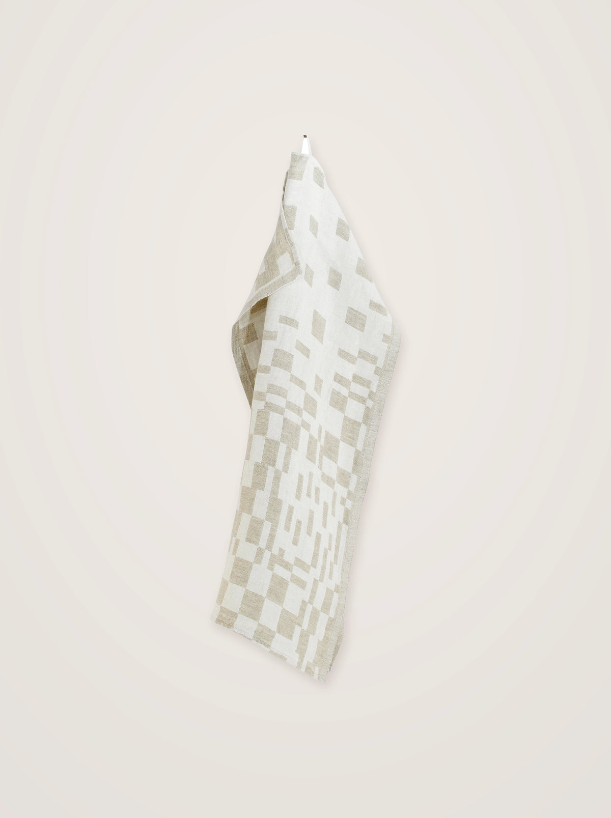 Washed linen towel hanging from its loop, showing the drape and woven checkered pattern