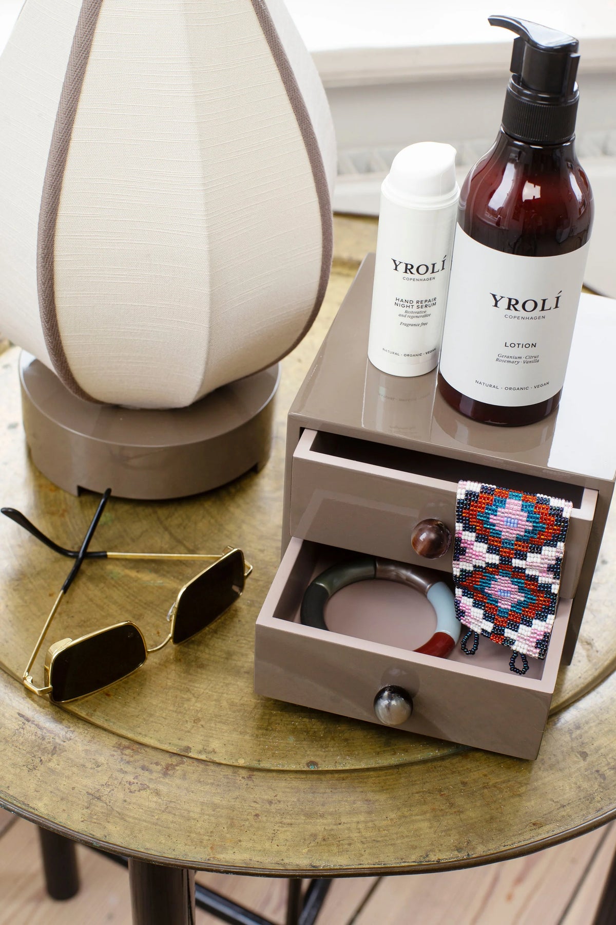 Lacquered jewellery chest holding bracelets in open drawers, with skincare bottles on top