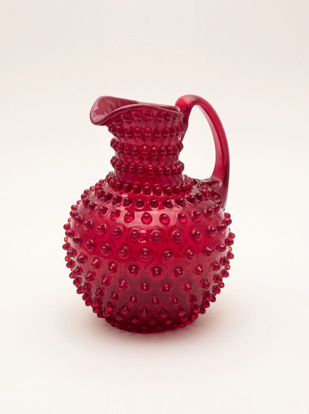 Garnet red hobnail glass jug with a bulbous body, curved handle and flared pouring spout