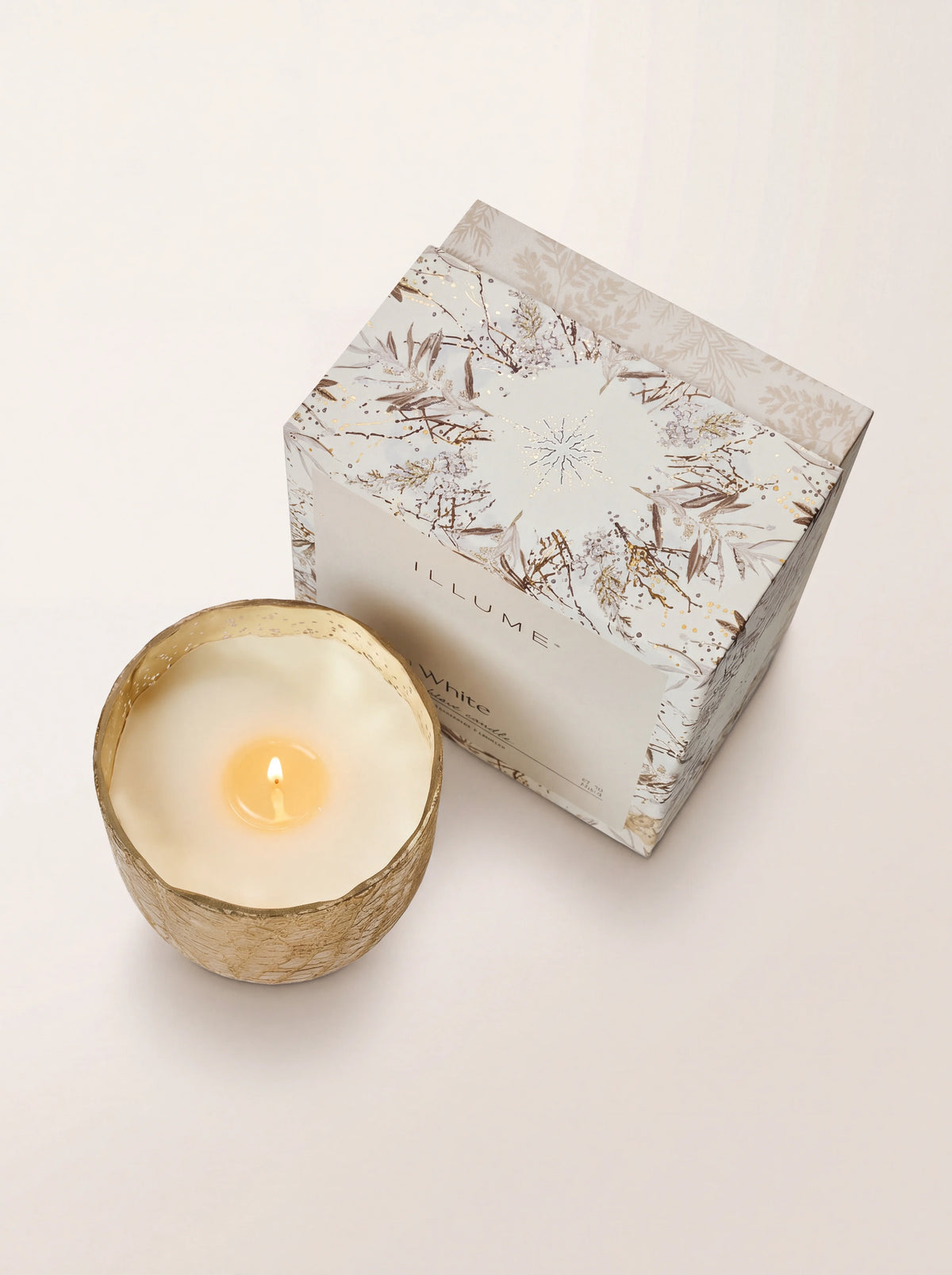 Lit scented candle viewed from above beside its illustrated gift box