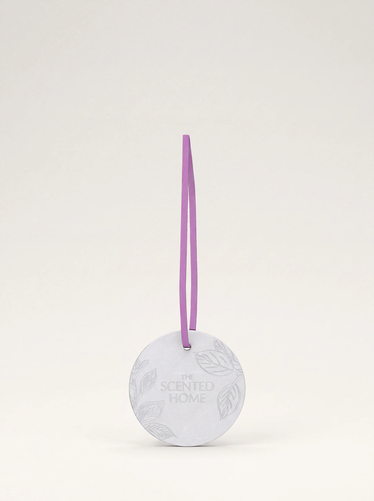 Round white ceramic disc embossed with leaf motifs, suspended by a lilac ribbon