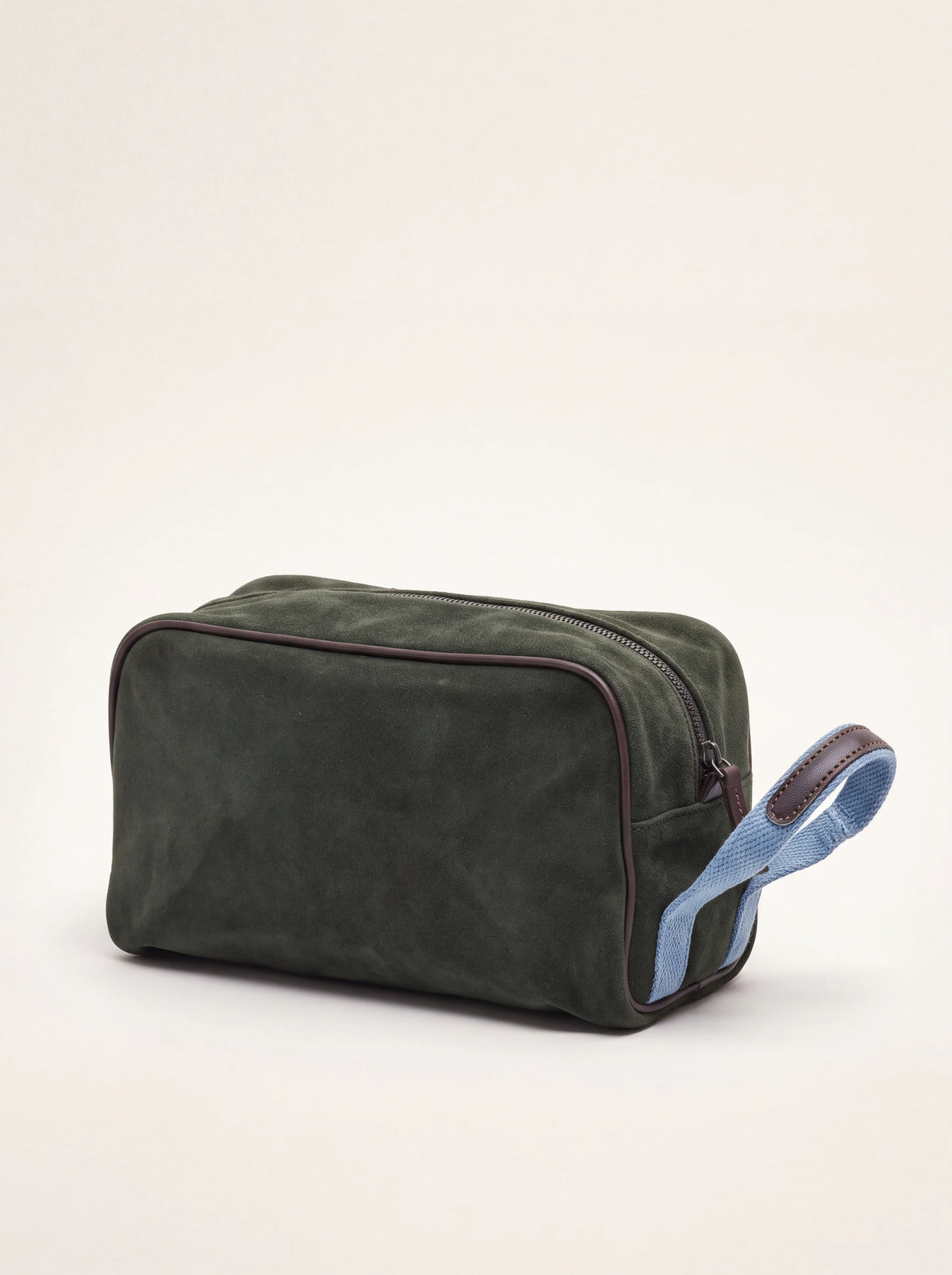 Dark green suede toiletry bag with brown leather piping and a light blue woven side handle