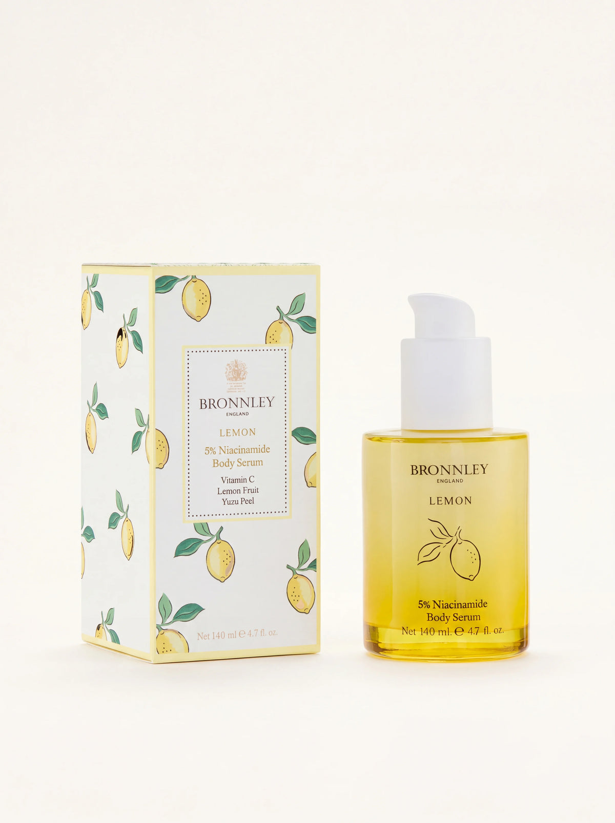 Lemon body serum in a clear glass bottle with a white pump dispenser, next to its lemon-patterned carton