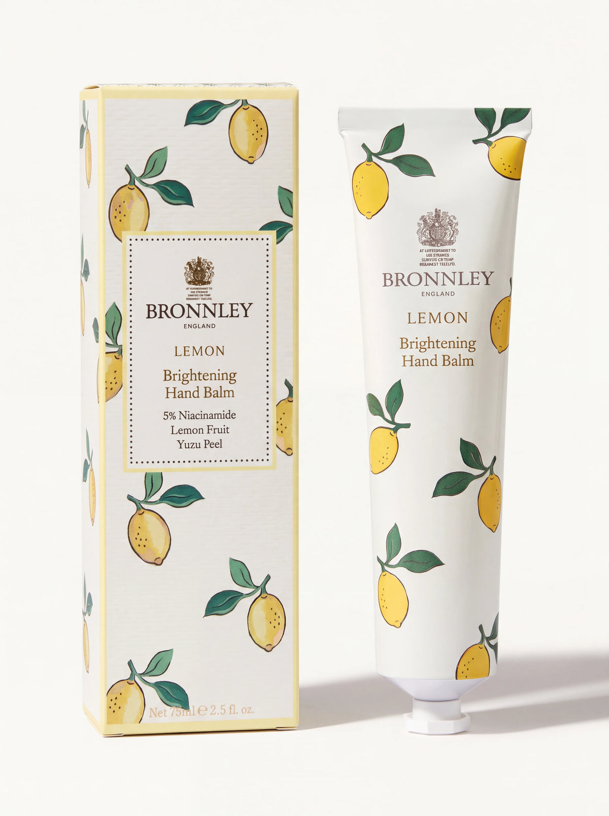 Lemon brightening hand balm in an aluminium tube beside its matching lemon-patterned carton