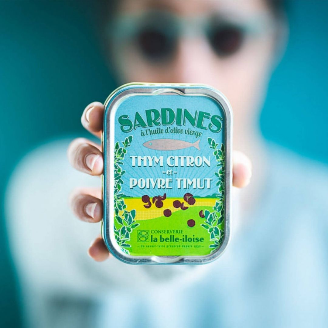 Sardine tin held in one hand, demonstrating its compact size and rectangular shape