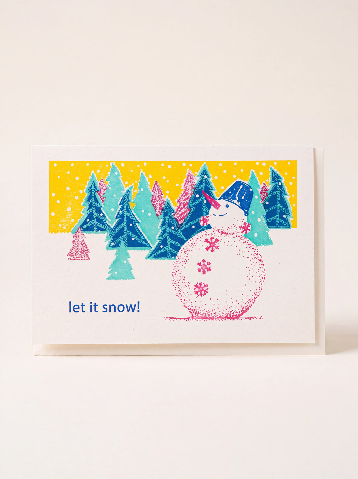 Recycled cardboard greeting card featuring an illustrated snowman, pine trees and the words 'let it snow!