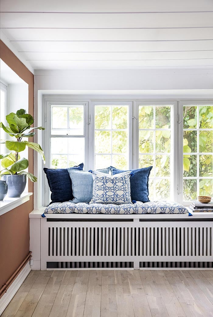 Blue linen cushion styled on a window seat bench among patterned cushions